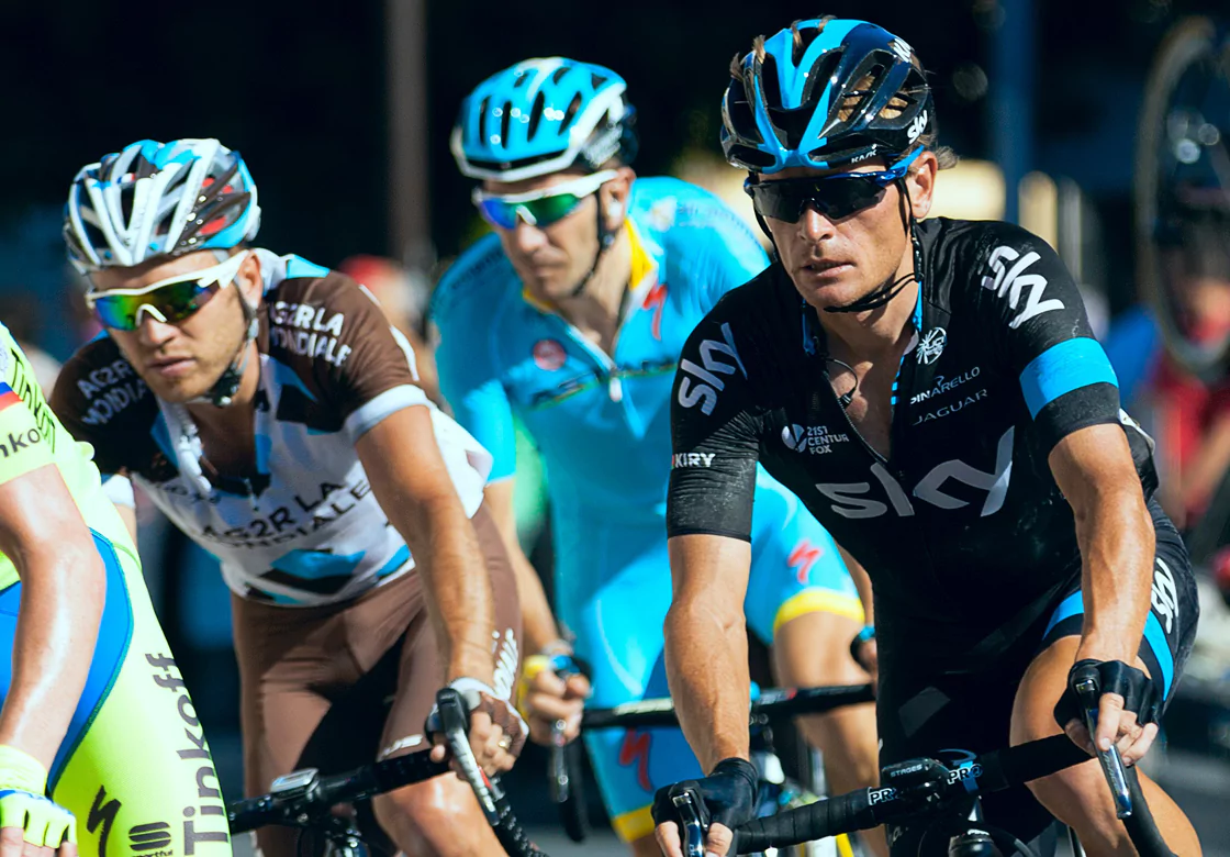 Three men in cycling uniforms race on a street