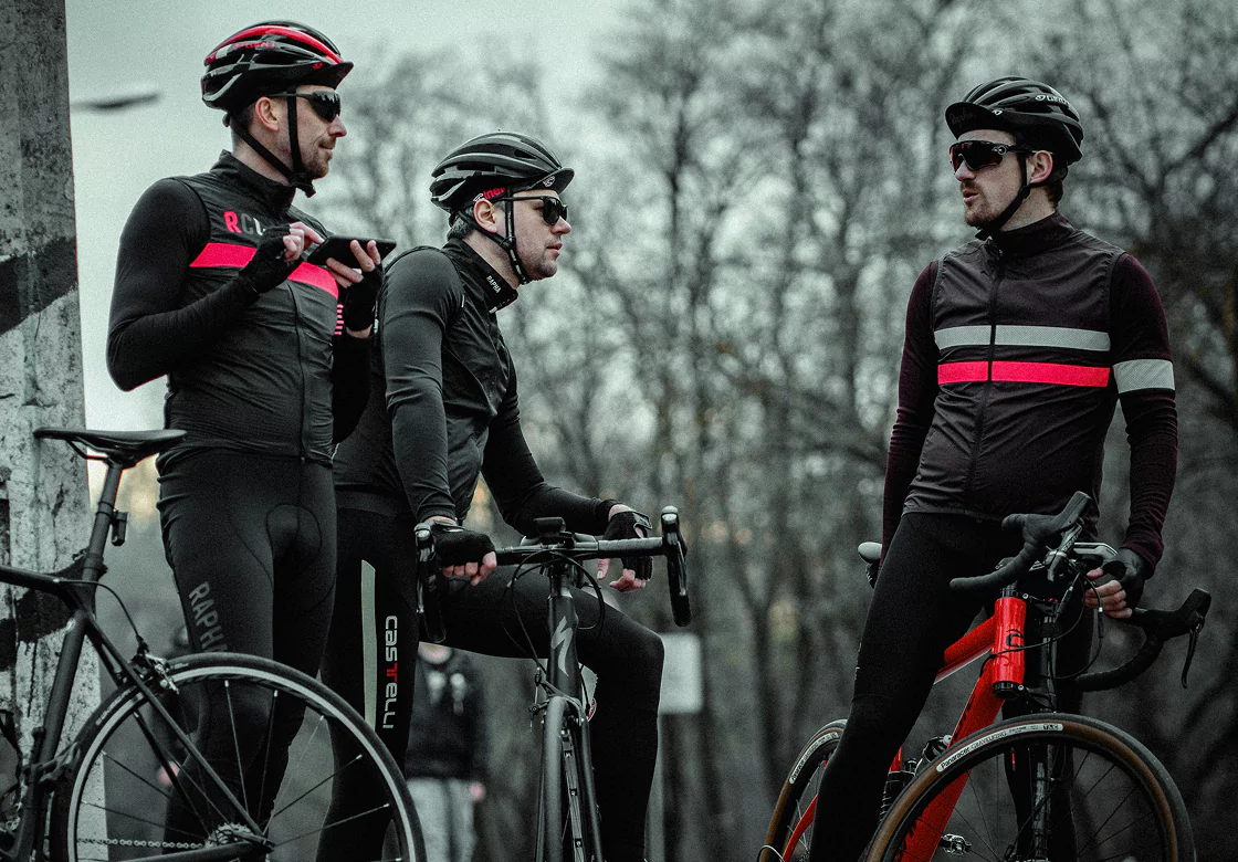 Three men standing side by side in cycling outfits.