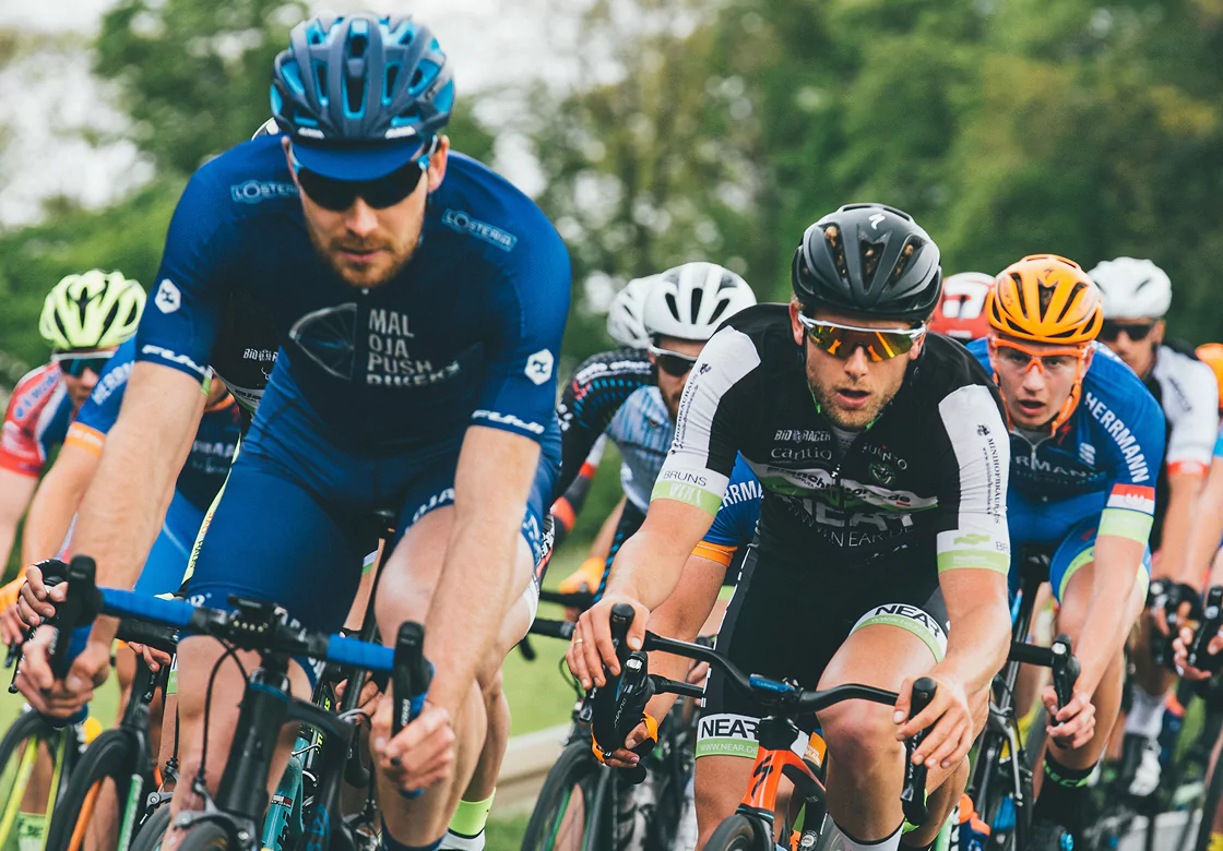 Men in cycling uniforms race on a street