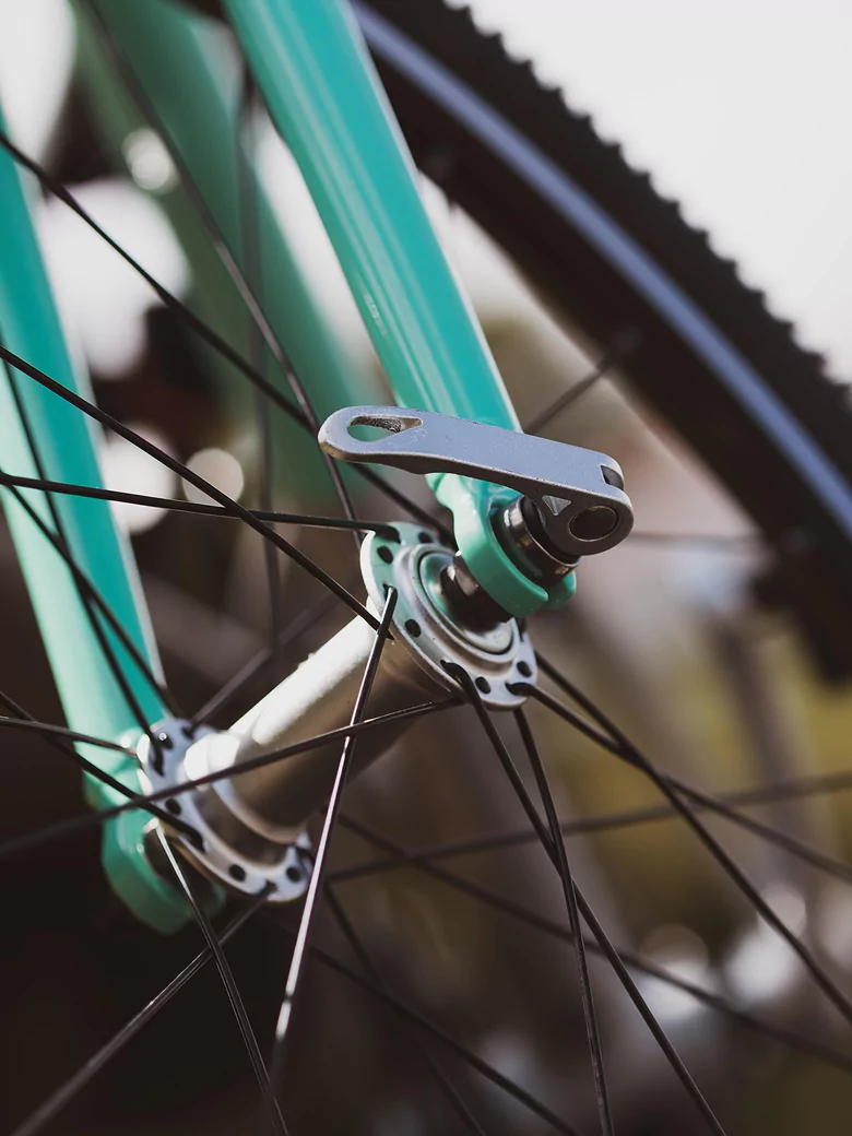 Close-up of a bicycle wheel showcasing a single spoke against a blurred background.